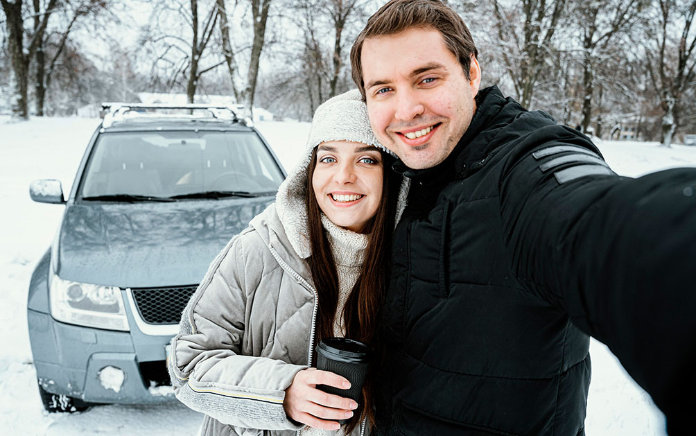 A couple on a snowy road taking a sefie.