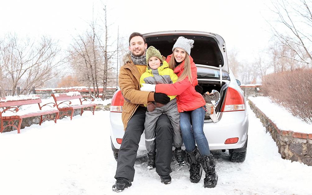 A family sits in their boot on a snow road happy with their snow socks from snowchainsandsocks.co.uk